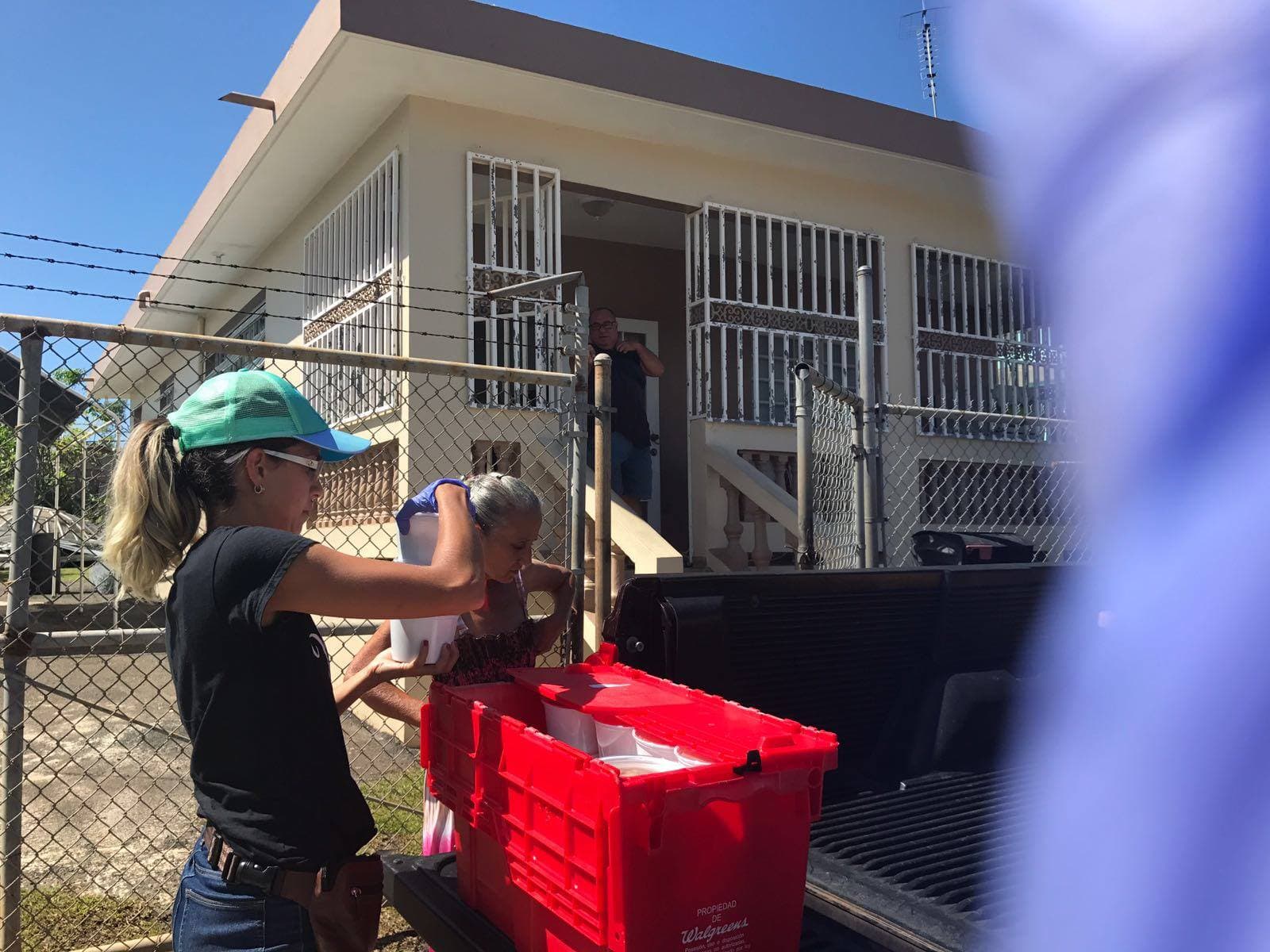 Volunteer handing food to elderly resident at home gate