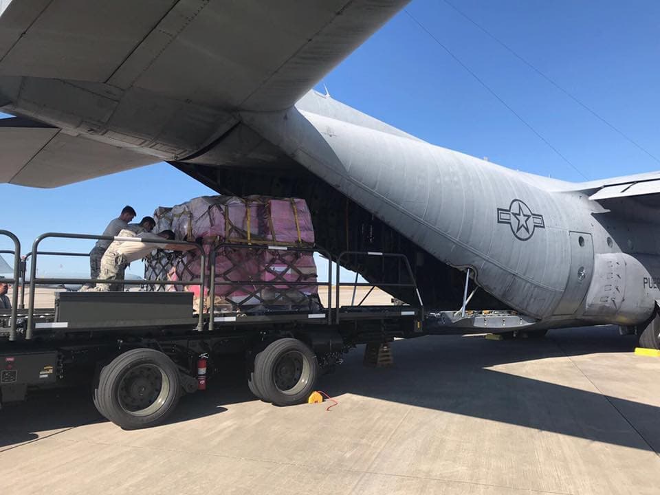 Airmen loading pallets into C-130 on the tarmac